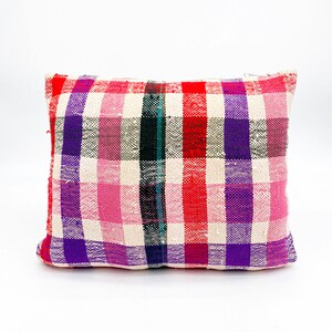 May include: A rectangular pillow with a white background and a plaid pattern in shades of pink, red, purple, and black.