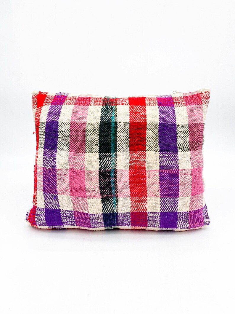May include: A rectangular pillow with a white background and a plaid pattern in shades of pink, red, purple, and black.