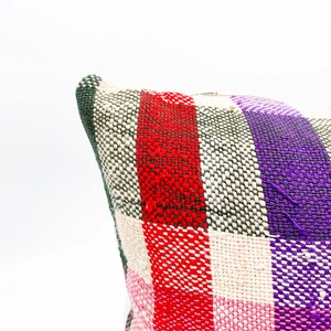 May include: A woven pillow cover with a plaid pattern in red, pink, green, and purple.