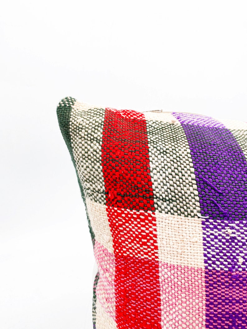May include: A woven pillow cover with a plaid pattern in red, pink, green, and purple.