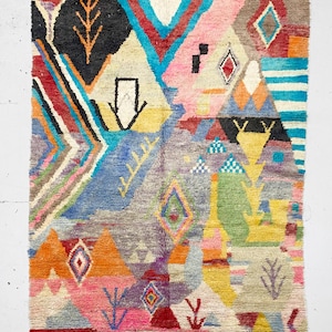 May include: A colorful, abstract rug with geometric patterns in shades of red, blue, yellow, green, and pink. The rug has a fringe border.