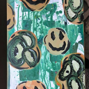 May include: Abstract painting on canvas with a green background and multiple smiley faces in different colours and styles. Some of the smiley faces have eyes and others have a more simple design.