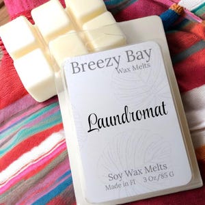 May include: A package of Breezy Bay wax melts in a clear plastic container. The label reads "Laundromat" and "Soy Wax Melts." The package contains six light yellow wax cubes. The product is 3 oz/85 g.