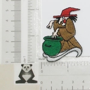 May include: An embroidered iron-on patch of a witch stirring a green cauldron with a red pointed hat and brown robe.