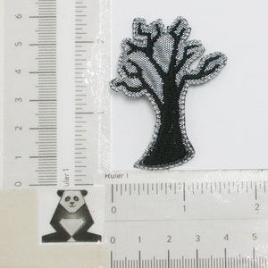 May include: An iron-on patch featuring a black and silver embroidered tree with a thick trunk and branches. The patch is approximately 5 cm tall.