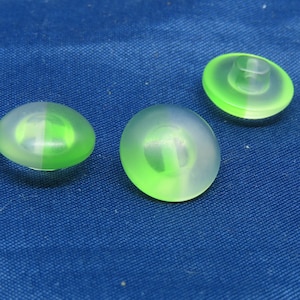 May include: Three green and clear plastic buttons with a raised center. The buttons are translucent and have a light green color.