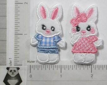May include: Two white felt bunny appliques, one wearing a blue and white striped shirt and the other wearing a pink and white polka dot dress.
