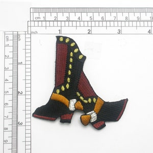 Peut inclure: Écusson brodé en forme de botte de cowboy. La botte est noire, bordeaux, dorée et orange. Le patch mesure environ 7,6 cm de haut.