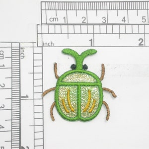 May include: Green embroidered iron-on patch of a beetle with gold accents.