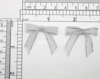 Puede incluir: Dos lazos de malla plateada con un brillo metálico. Los lazos miden aproximadamente 5 cm de ancho.