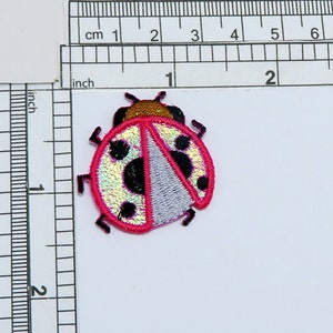 Op de afbeelding: Geborduurde lieveheersbeestjespatch met een rode omtrek, zwarte stippen en een zilveren en iriserende body. De patch meet ongeveer 3,2 cm in lengte en breedte. Het lieveheersbeestje heeft een gouden kop en zwarte antennes.