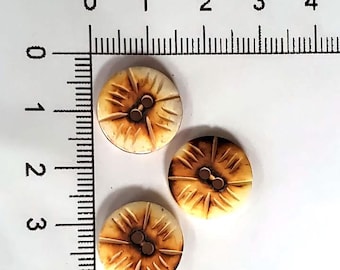 Puede incluir: Tres botones marrones y blancos con un diseño decorativo. Los botones tienen dos agujeros y miden aproximadamente 2,5 cm de diámetro.