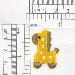 May include: Yellow felt giraffe applique with brown felt accents. The giraffe has white spots and a yellow outline. The applique is approximately 1 inch tall.
