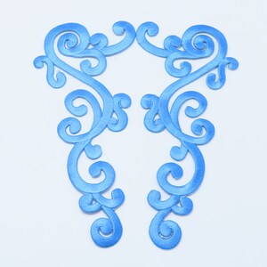 May include: A pair of blue embroidered fabric appliques with a delicate, swirling design. The appliques are ideal for adding a touch of elegance to clothing, crafts, or home decor.