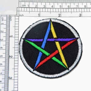 May include: A black and white embroidered patch with a five-pointed star in the center. The star is outlined in red, yellow, blue, and green thread.