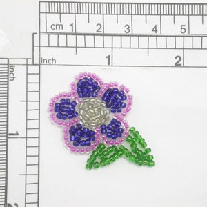 May include: A purple and blue beaded flower with a green stem and leaves. The flower is approximately 2.5 cm in diameter.