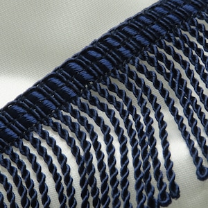 May include: Close-up of a navy blue twisted fringe trim. The fringe is made of a soft, silky material and has a subtle sheen.
