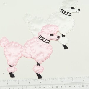 May include: Two embroidered poodle patches, one pink and one white, with black collars and eyes. The patches are on a white background.