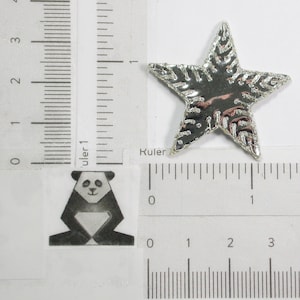 Op de afbeelding: Een zilveren stervormige versiering met een gestructureerd oppervlak. De ster is ongeveer 2,5 cm in diameter.
