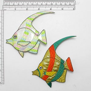 May include: Two embroidered iron-on patches of colorful fish. One fish is green, yellow, and orange. The other fish is white, green, and pink.