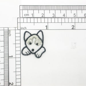 Può includere: Toppa da stiro ricamata bianca e grigia di un cane husky con occhi neri. La toppa è larga circa 2 cm.