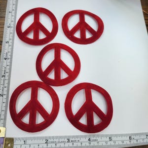 Peut inclure: Cinq symboles de paix en feutre rouge. Les symboles de paix mesurent environ 5 cm de diamètre.