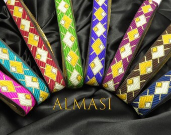 May include: Assortment of colorful fabric trim with a geometric diamond pattern. The trim features gold, white, and various colors including teal, purple, brown, green, and blue. The trim is arranged in a fan shape with the text "ALMASI" at the bottom.