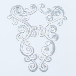 May include: A pair of silver embroidered appliques with a delicate, swirling design. The appliques are perfect for adding a touch of elegance to clothing, crafts, or home decor.