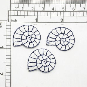 May include: Three white embroidered iron-on patches of seashells with a blue outline. The shells are in a spiral shape.