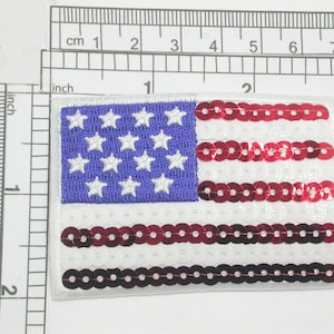 May include: A red, white, and blue American flag patch with a sequined design. The stars are white on a blue background, and the stripes are red sequins on a white background.