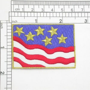 May include: A blue and red embroidered patch with a gold outline. The patch features a stylized American flag with five gold stars in the blue canton and red and white stripes.
