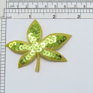 May include: A green and yellow sequined leaf applique. The leaf is approximately 5 cm wide.
