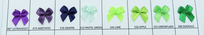May include: A selection of ten small satin bows in various colors, including ultraviolet, amethyst, grappa, pastel green, lime, apple, greenflash, and emerald. The bows are arranged in a row on a white background.
