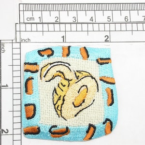 Peut inclure: Un patch brodé bleu et orange avec une image stylisée jaune et blanche d'une abeille.