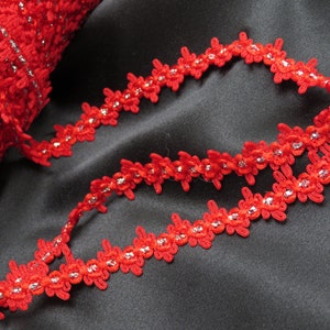 May include: Red and silver floral trim with a scalloped edge. The trim is made of a soft, flexible material and has a delicate, feminine look.