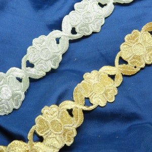 May include: Two pieces of decorative trim with a floral design. One trim is gold and the other is silver.