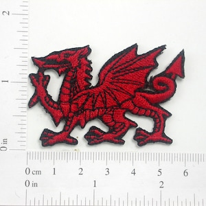 Peut inclure: Patch brodé rouge représentant le dragon gallois, une créature mythique avec des ailes et une longue queue. Le dragon est tourné vers la droite et a un contour noir.