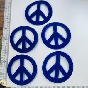 Peut inclure: Cinq découpes de signe de paix en velours bleu. Les signes de paix mesurent environ 5 cm de diamètre.