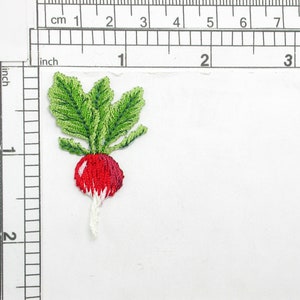 Könnte beinhalten: Gestickter Radieschen-Aufnäher mit leuchtend roter Knolle und grünen Blättern. Der Aufnäher ist etwa 4 cm hoch und zeigt detaillierte Stickereien und ein realistisches Design. Ideal, um Kleidung oder Accessoires einen Hauch von Laune zu verleihen.