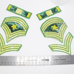 May include: Set of five green and yellow sequined patches, including two chevron patches, two smaller rectangular patches, and one larger patch with a star in the center.