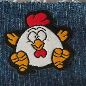 May include: A white chicken with red and yellow accents, embroidered on a blue denim fabric.