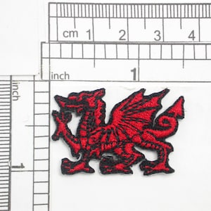 May include: Red embroidered patch of a Welsh dragon with black outlines. The dragon is facing right and has wings spread out.