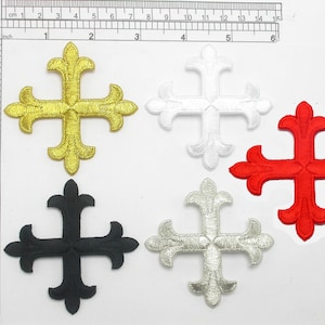 May include: Four iron-on patches in the shape of a cross with a fleur-de-lis design. The crosses are gold, white, black, and red.