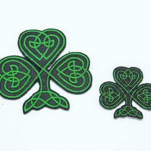 Könnte beinhalten: Zwei grüne Kleeblatt-Patches mit komplizierten keltischen Knotendesigns. Der größere Patch ist etwa 10 cm breit und der kleinere Patch etwa 5 cm breit.