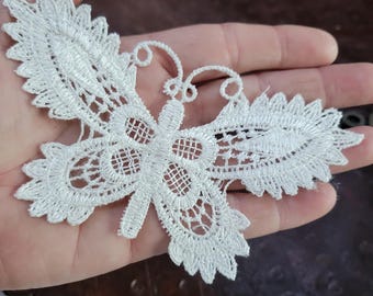 Applicazione da cucire con motivo a farfalla in pizzo veneziano color bianco sporco.