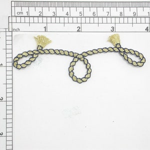 Könnte beinhalten: Gold- und schwarz geflochtener Besatz mit Quasten an jedem Ende. Der Besatz ist etwa 7,5 cm lang.