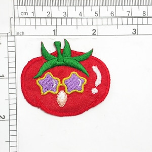 May include: Red embroidered tomato patch with green leaves and purple star-shaped sunglasses. The tomato has a white exclamation point on the side.