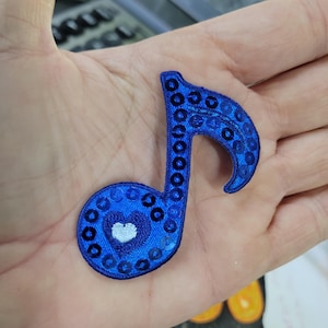 Parche de nota musical con lentejuelas azules. Medidas: 2 1/8" x 2 3/8"
