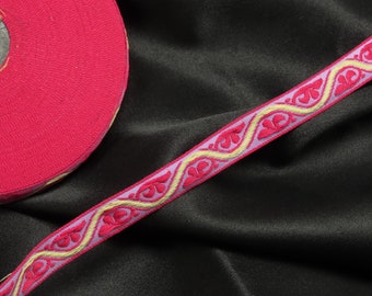 May include: A pink and gold trim with a floral design. The trim is on a black fabric background.