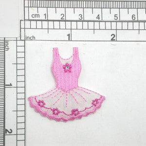 May include: Pink ballerina dress applique with a white tulle skirt and pink floral embroidery. The dress has a single rhinestone in the center of the bodice.